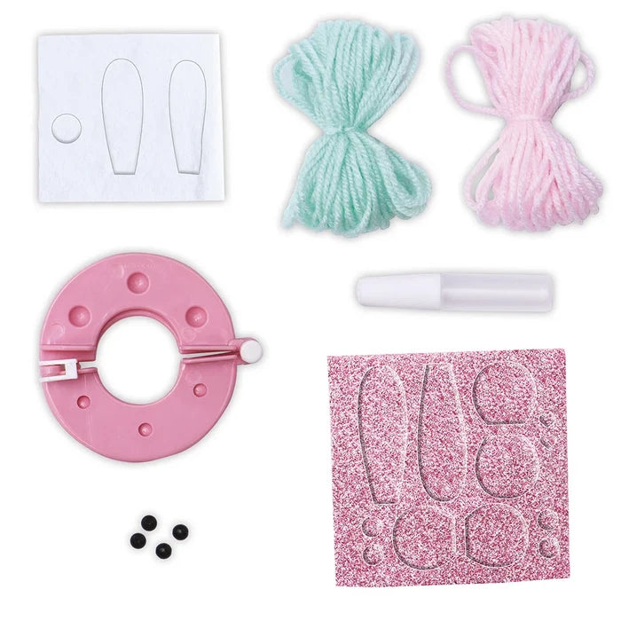 Craft kit with pink and mint yarn, pink pom-pom maker, glue, glittery foam shapes, white felt pieces, and black beads.