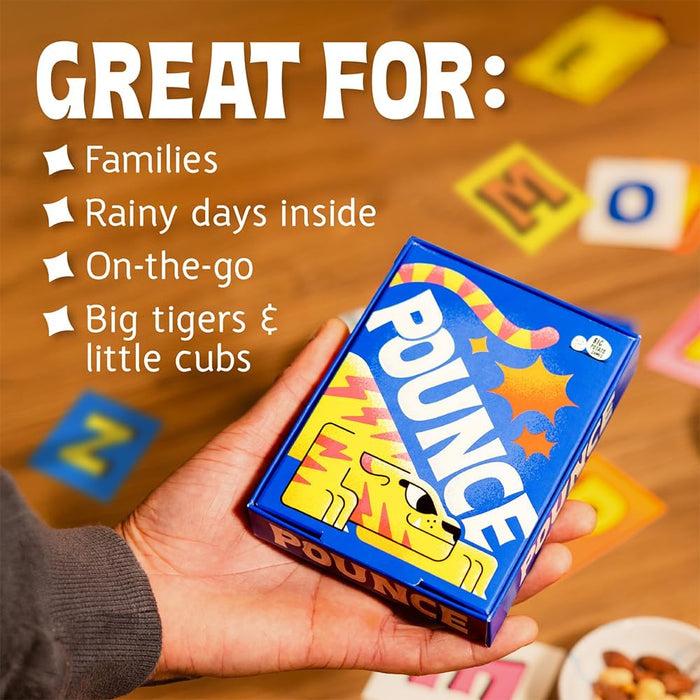 A hand holds the blue Pounce card game box over a wooden table with colorful letter tiles and text about who it's great for.