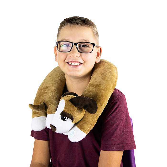 A young boy wearing a tan and white plush puppy neck pillow with a power button on the front paw.