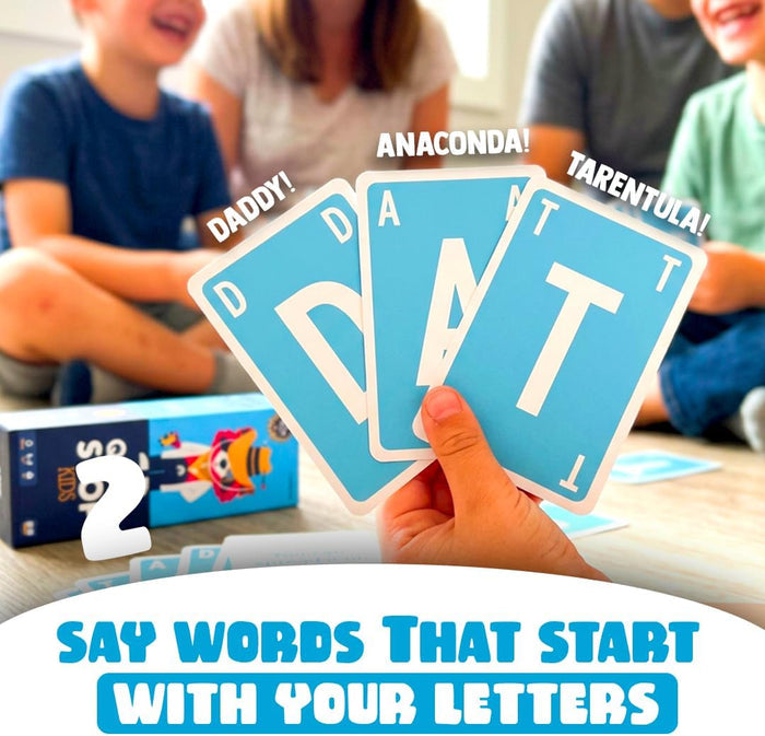 Hand holding blue D, A, and T letter cards with word bubbles. A family plays on the floor near the blue game box.