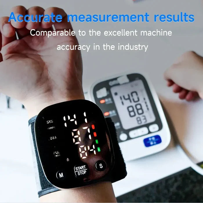 Close-up of a person using a Rechargeable Digital Wrist Blood Pressure Monitor displaying readings with another monitor in the background.