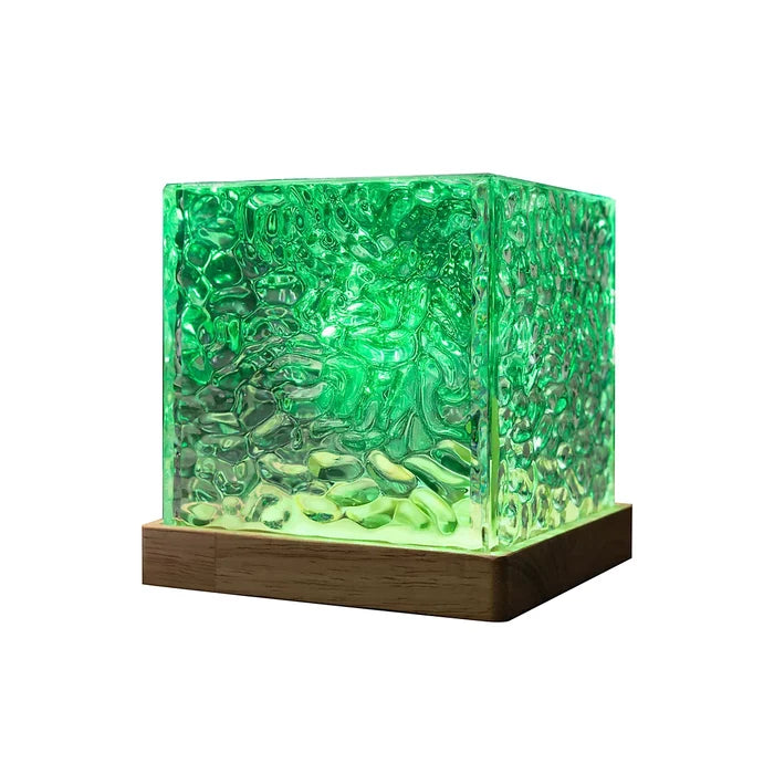 Green glowing cube lamp with ripple-textured glass on a square wooden base.