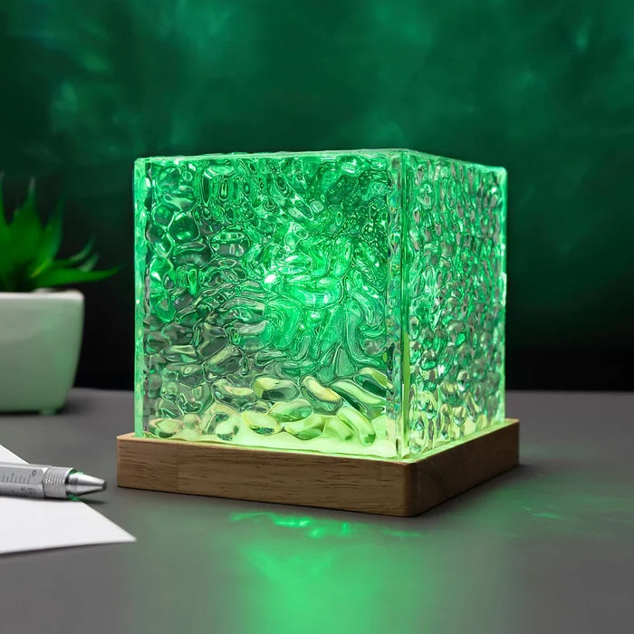Green glowing cube lamp with textured rippled glass on a wooden base, projecting a northern lights effect.