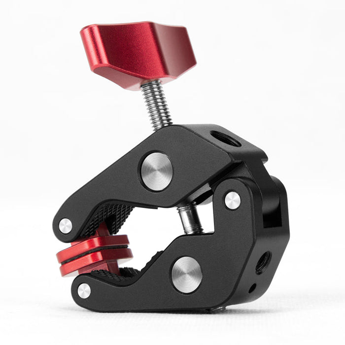 Angled view of a compact Super Clamp with a red aluminum knob, black metal body, and textured jaws for secure grip on rods or flat surfaces.