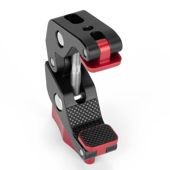 Close-up of a Super Clamp with textured rubber grip pads, red and black aluminum body, and threaded screw for tightening onto surfaces.