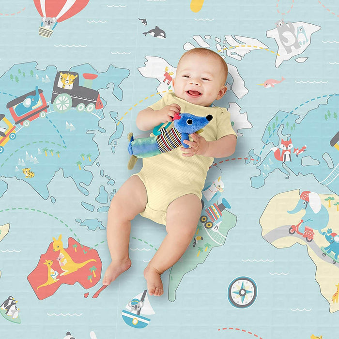 Smiling baby on a blue world map playmat with cartoon animals and vehicles, holding a blue plush toy.