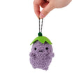 Fuzzy purple eggplant-shaped plush with tiny black eyes and a green leaf top, hanging from a black ball chain.