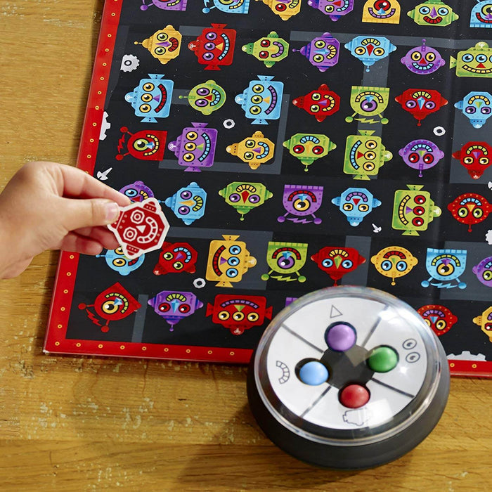 Hand matching a red robot chip to a game board of various colorful robot faces next to a shaker device.
