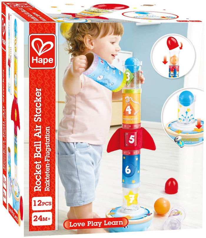 Toddler playing with a colorful numbered rocket stacking toy next to its red and white product packaging.