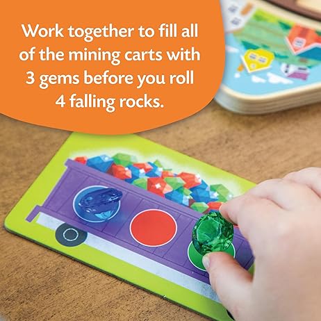 Child's hand placing a green gem on a purple mine cart card. An orange speech bubble explains the game's cooperative goal.