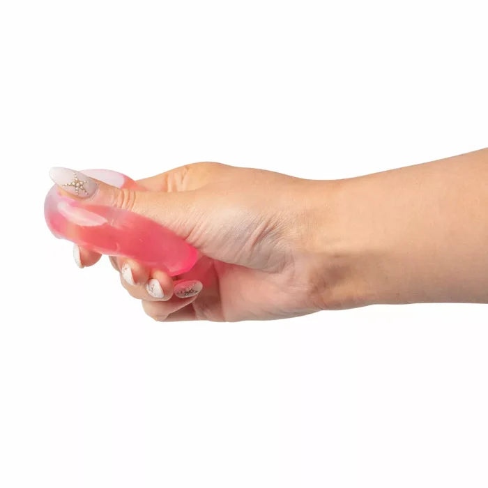 Hand squeezing a soft, translucent pink cube-shaped squishy toy.