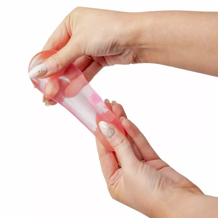 Two hands stretch a pink, translucent gel-filled squishy toy against a white background.