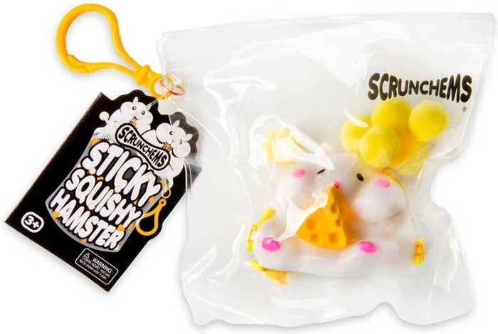 White squishy hamster toy holding cheese in a clear bag with yellow pom-poms, a black tag, and a yellow clip.