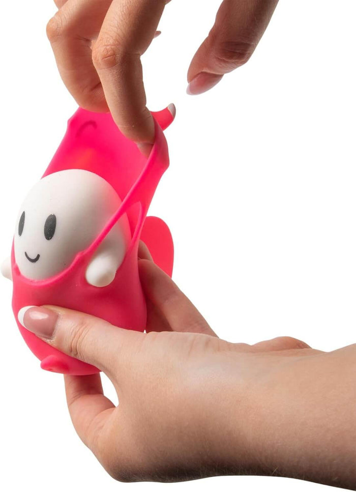 Hands stretching a pink silicone sleeve to reveal a small white ghost toy with a simple smiling face.