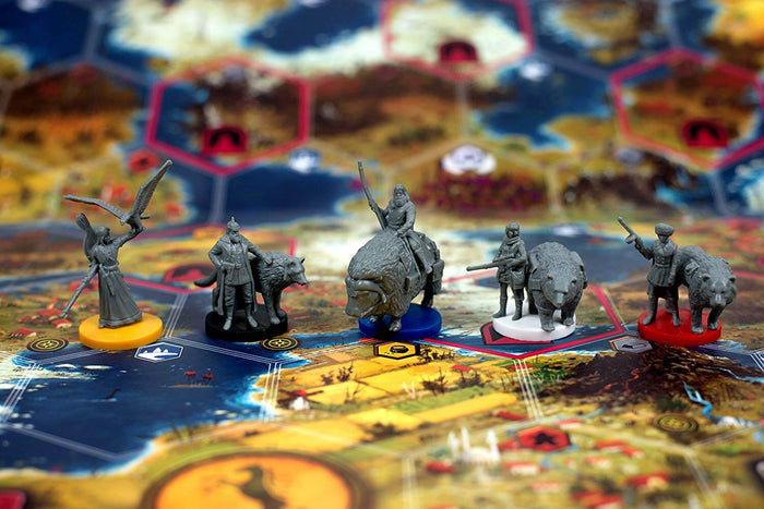 Five grey plastic miniatures of characters and animals on colored bases atop a detailed hexagonal-grid game map.