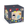 Dark blue box showing a wooden Janod sensory cube with a red horn, mirrors, and colorful shape icons for ages 18m+.