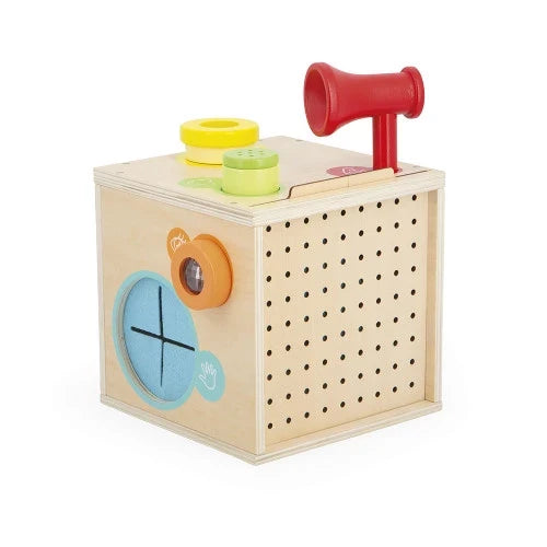 Light wood sensory toy cube with a red horn, colorful top buttons, blue cross-cutout, and a perforated side.
