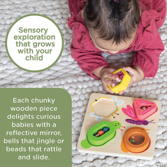 Baby playing with a wooden sensory puzzle featuring colorful butterfly, bee, and beetle pieces on a white textured rug.