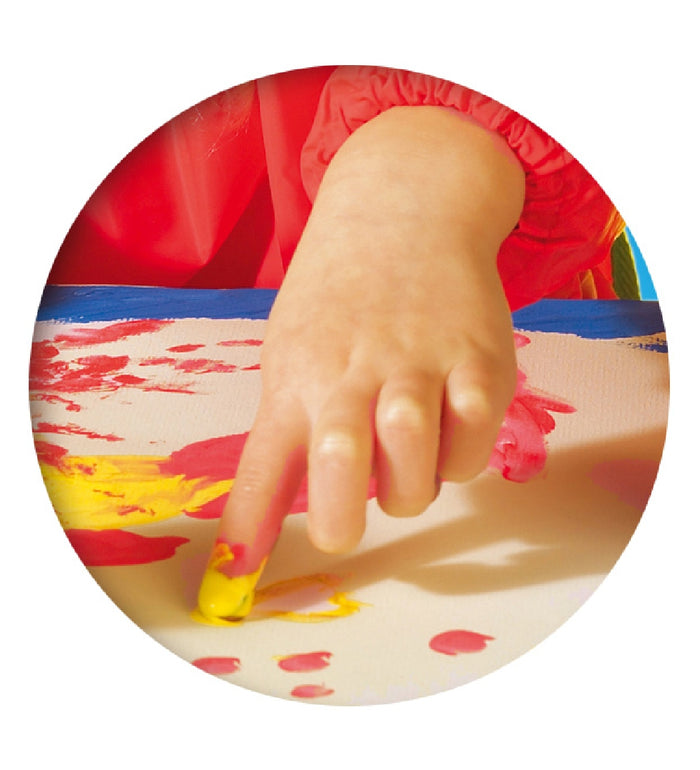 Close-up of a young child's hand using yellow and red finger paint to create colorful marks on white paper.