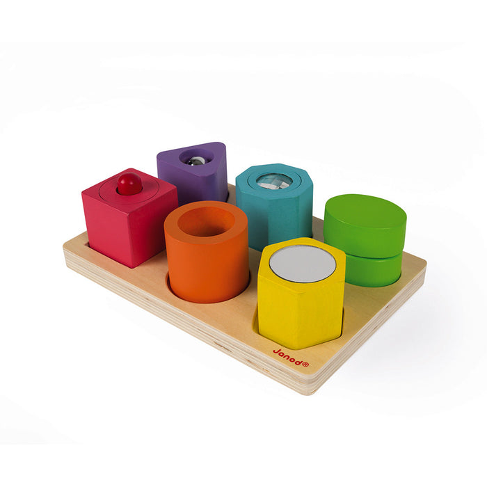 Six colorful wooden blocks of various shapes with a mirror, bell, and lens on a light wood puzzle base.