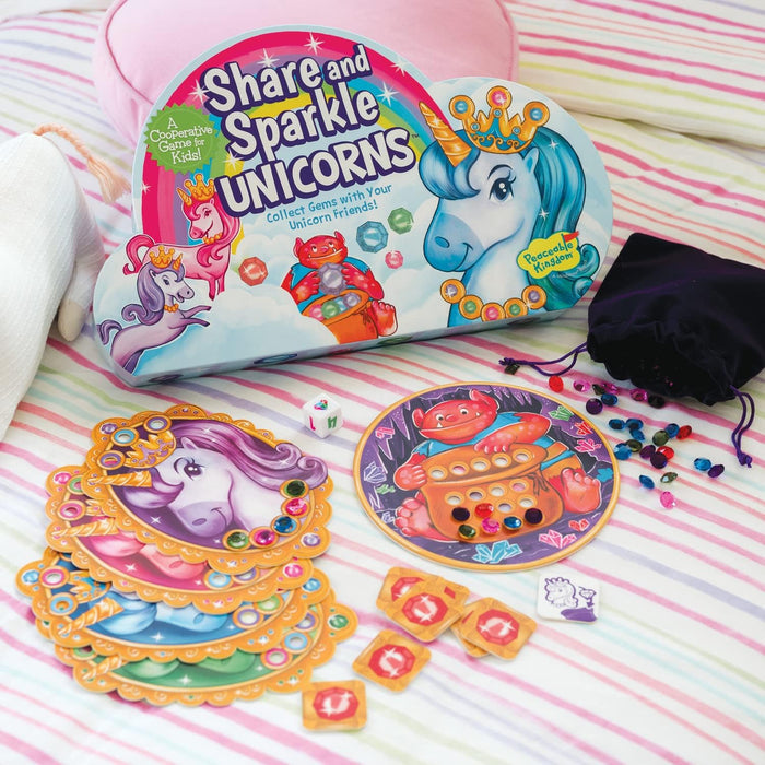 Cloud-shaped game box with unicorns, scalloped character boards, colorful plastic gems, and dice on a striped surface.
