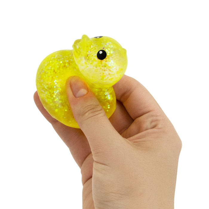 Hand squeezing a yellow, translucent duck-shaped squishy toy filled with shimmering glitter.
