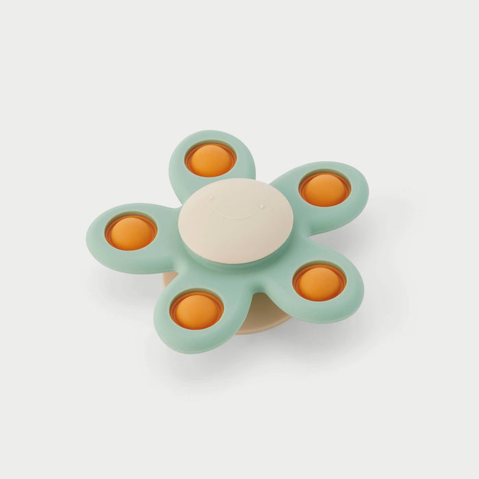Flower-shaped spinner toy with five sage green petals, orange pop buttons, and a smiling cream center.