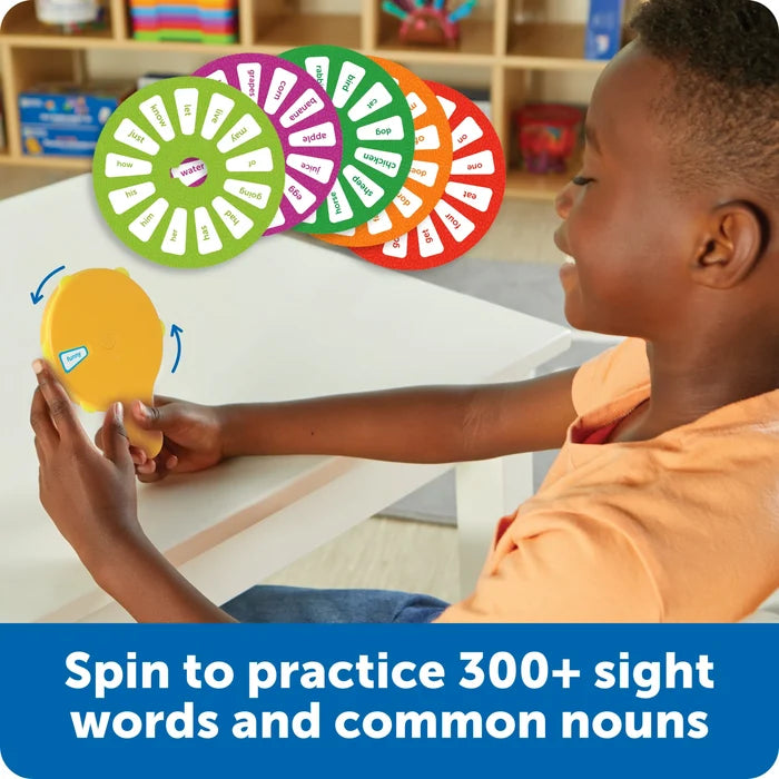 Child uses a yellow handheld wheel next to colorful circular discs printed with sight words and common nouns.
