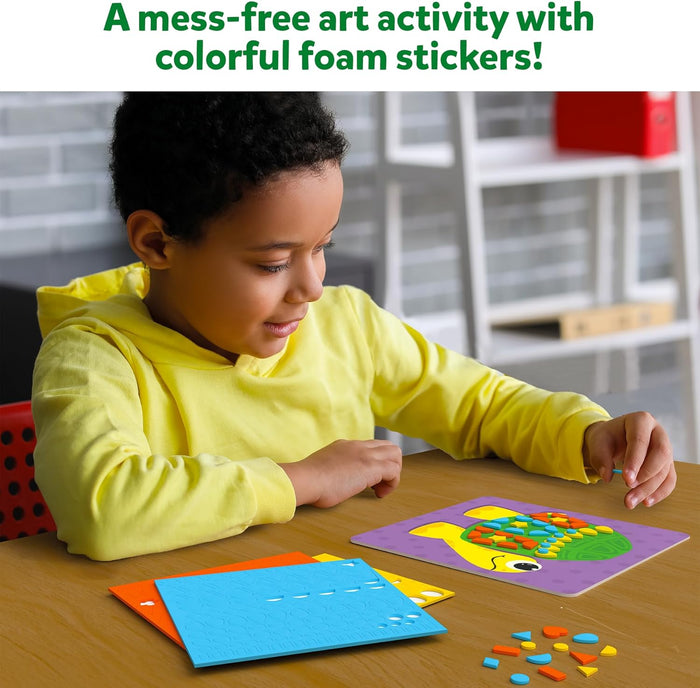 Child in a yellow hoodie applying colorful foam sticker shapes onto a purple turtle art card.