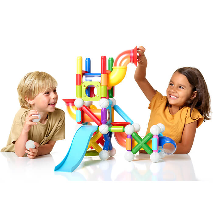 Children building a colorful magnetic ball run with bright rods, white spheres, tubes, and a blue slide.