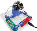 Toy circuit board with blue snap connectors and a black dome projecting a glowing moon and star light pattern.