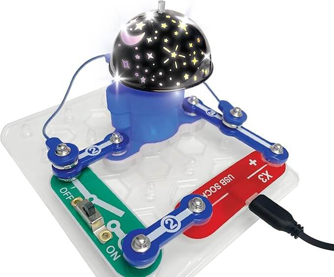 Toy circuit board with blue snap connectors and a black dome projecting a glowing moon and star light pattern.