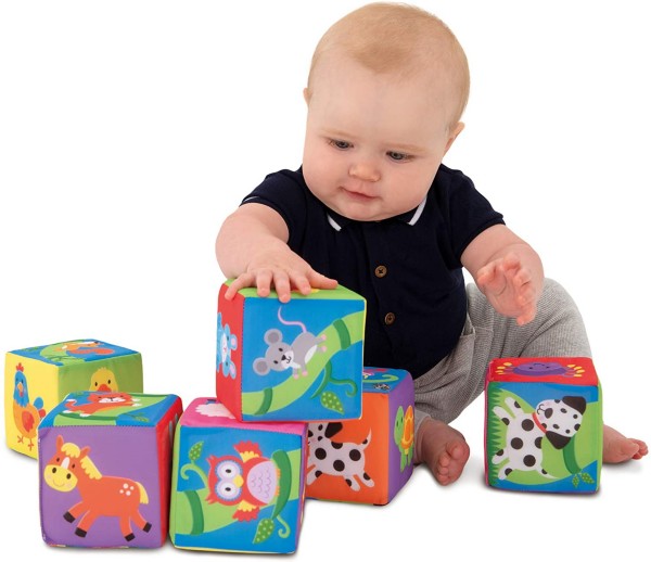Baby playing with six colorful soft fabric blocks featuring illustrations of animals like a horse and a dog.