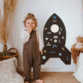 Black rocket-shaped magnetic wall board with colorful geometric magnets and a white circular window.