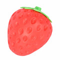 A red strawberry-shaped squishy toy with green leaves and a textured surface featuring small indentations.