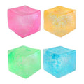 Four translucent squishy cubes in pink, orange, green, and blue, each filled with shimmering glitter.