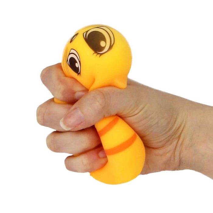 Hand squeezing a yellow-orange cat-shaped squishy toy with large cartoon eyes and orange stripes.