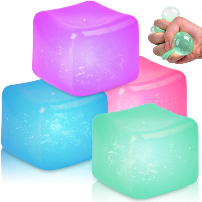 Four colorful, translucent squishy cubes in purple, pink, blue, and green, with a hand squeezing the green cube.