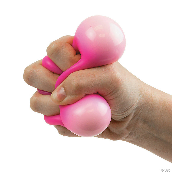 Hand squeezing a soft, pink, two-lobed sensory toy with squishy material bulging between the fingers.