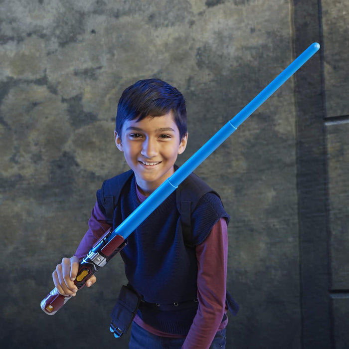 Smiling child holds a toy lightsaber with a blue extendable blade and a maroon, silver, and black hilt.