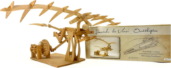 Assembled light wood model of a winged machine with gears and a hand crank, shown next to its illustrated product box.