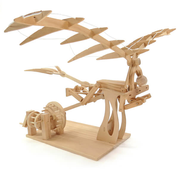 Light wood mechanical model of a flying machine with large ribbed wings and a hand-cranked gear system on a base.