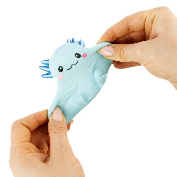 Hands stretching a squishy light blue axolotl toy with a cute face and blue gills against a white background.