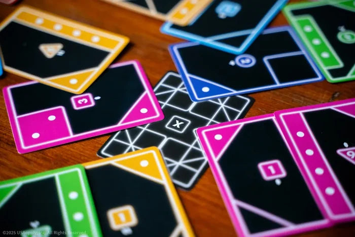 Colorful neon geometric game cards with dots and numbers scattered across a wooden surface.