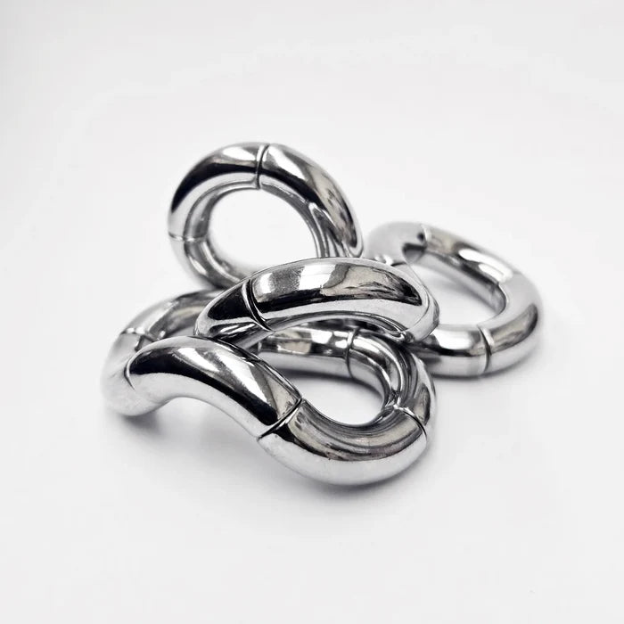 Shiny silver kinetic sculpture of interconnected, rotating curved metal segments twisted into an abstract shape.