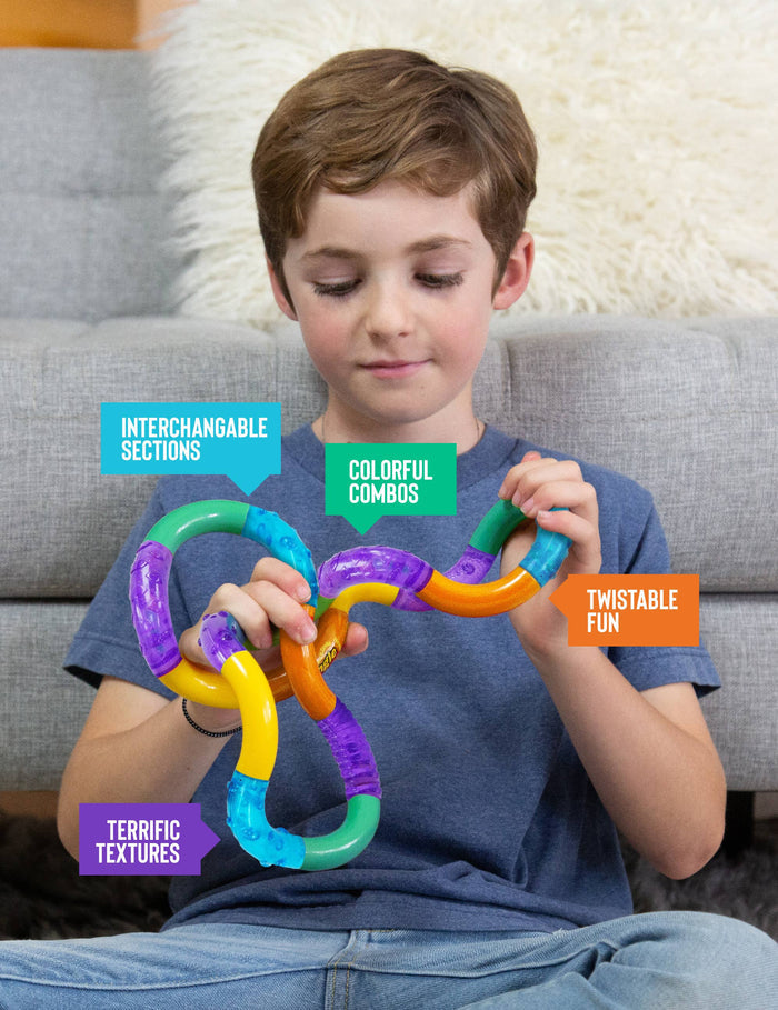 A young boy sitting on a gray couch holds a colorful magnetic toy chain with interlocking pieces. Text callouts highlight features like interchangeable sections, colorful combos, twistable fun, and terrific textures.