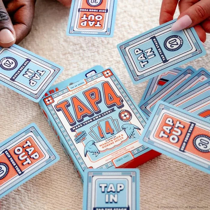 Teal and orange Tap 4 card game box surrounded by matching playing cards held by hands on a tan textured surface.