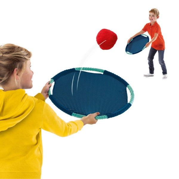Two children playing catch with blue circular mesh paddles and a soft red ball. Large teal-rimmed racket in foreground.