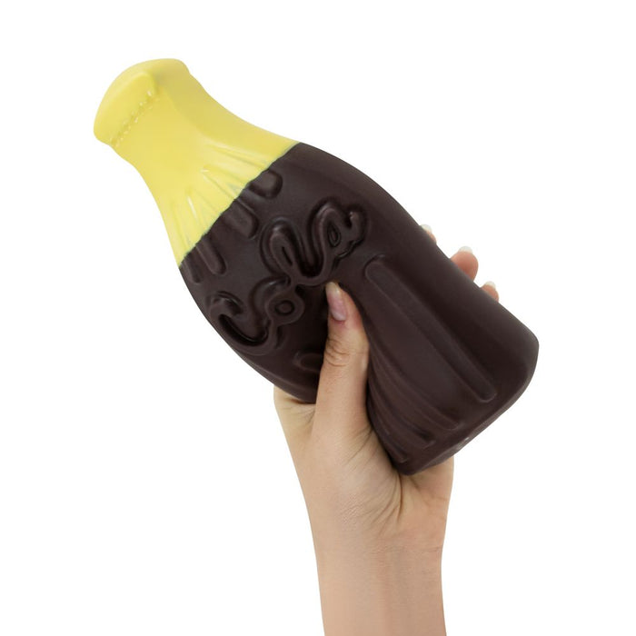 Hand squeezing a brown and yellow cola bottle squishy toy with embossed "Cola" lettering.