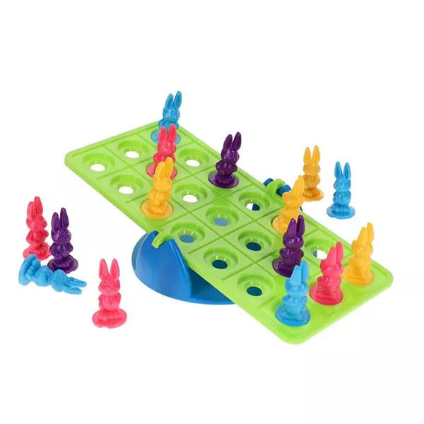 Colorful plastic bunny figures on a green rectangular seesaw board with circular holes and a blue base.